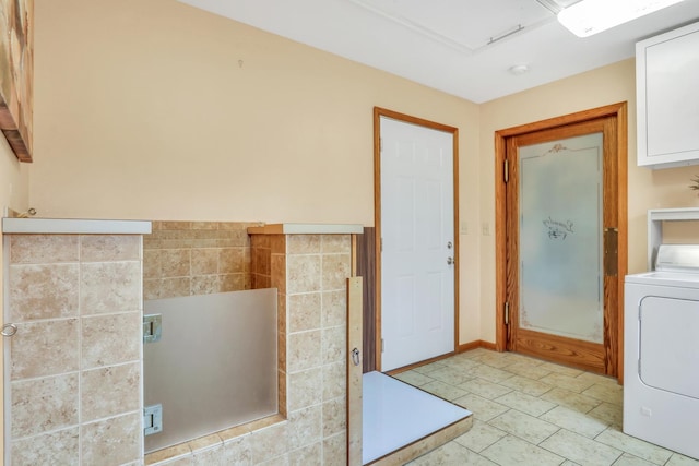 interior space featuring washer / clothes dryer, cabinet space, and light tile patterned floors