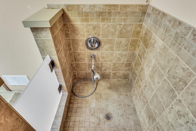 full bath featuring visible vents and tiled shower