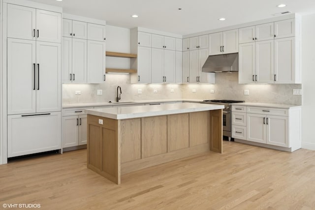 kitchen featuring sink, high end range, a center island, light wood-type flooring, and white cabinets