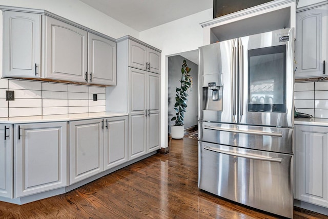 kitchen featuring stainless steel refrigerator with ice dispenser, dark hardwood / wood-style floors, gray cabinets, and backsplash