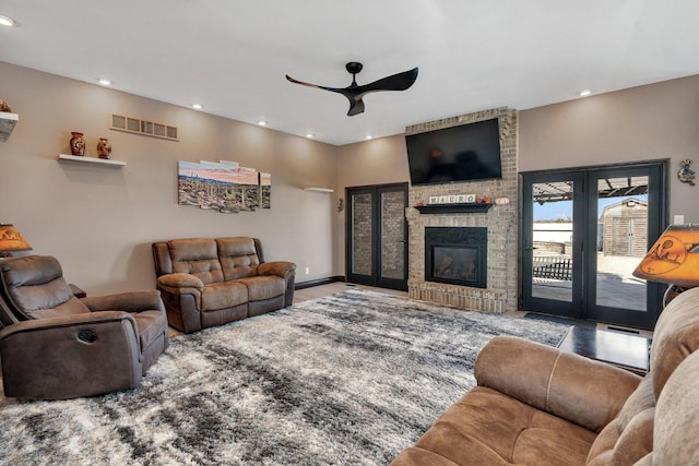 living room with french doors, ceiling fan, and a brick fireplace