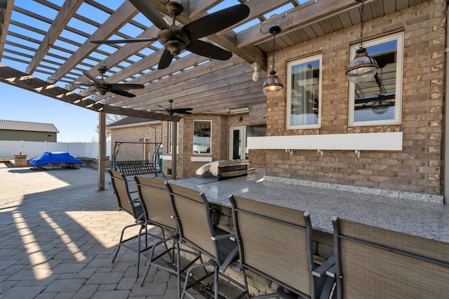 view of patio featuring an outdoor kitchen, an outdoor bar, ceiling fan, and a pergola