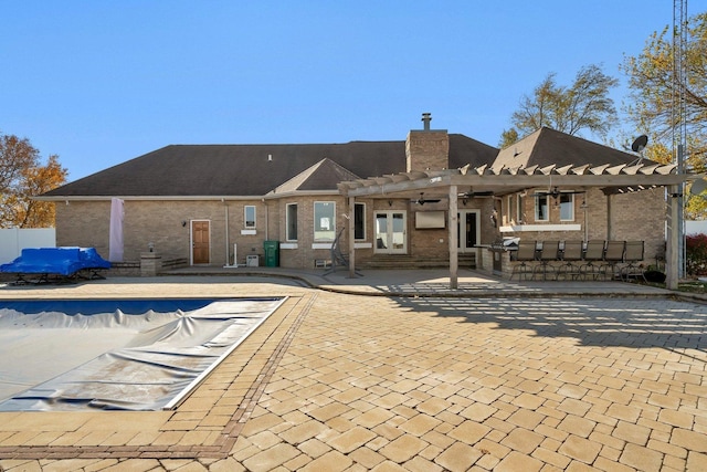 rear view of property with a pergola, a patio area, and a covered pool