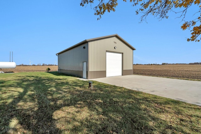 view of outdoor structure featuring a rural view, a garage, and a lawn