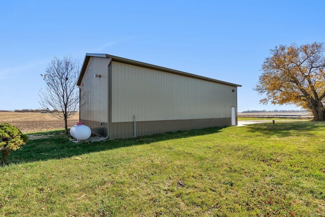 view of side of home featuring a lawn and a rural view