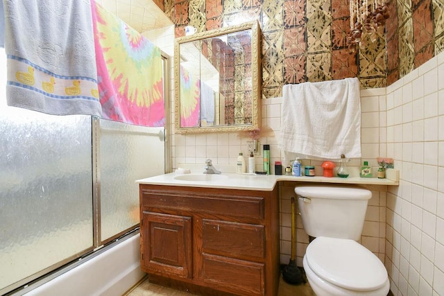 full bathroom featuring enclosed tub / shower combo, vanity, toilet, and tile walls