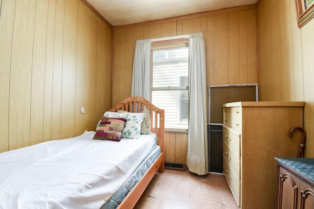 bedroom with light parquet floors and wood walls