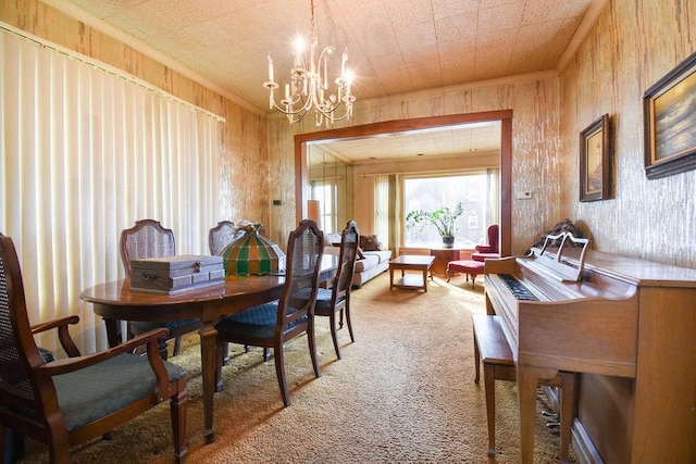 carpeted dining room with wood walls, ornamental molding, and a notable chandelier