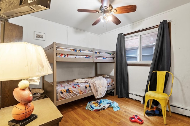 bedroom featuring hardwood / wood-style flooring, ceiling fan, and baseboard heating