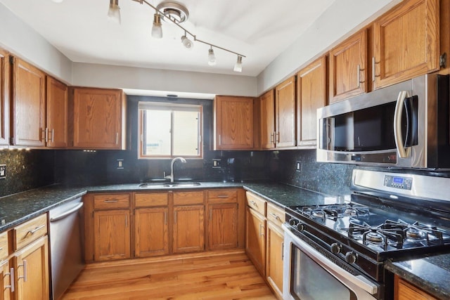 kitchen with stainless steel appliances, sink, dark stone countertops, and backsplash