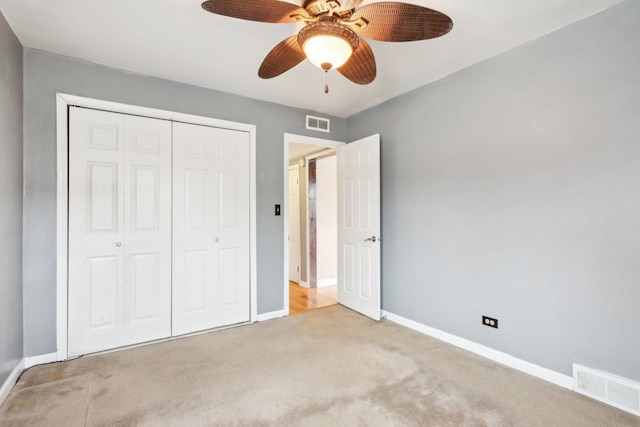 unfurnished bedroom with light colored carpet, ceiling fan, and a closet