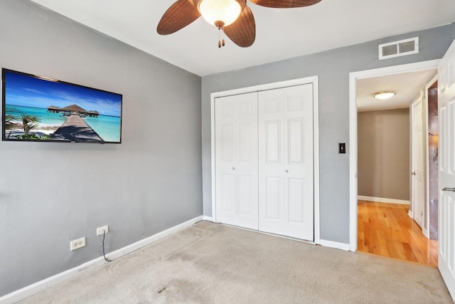 unfurnished bedroom with ceiling fan, light colored carpet, and a closet