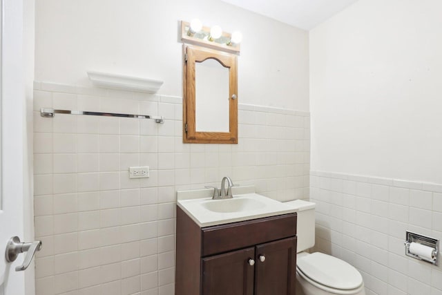 bathroom with vanity, toilet, and tile walls