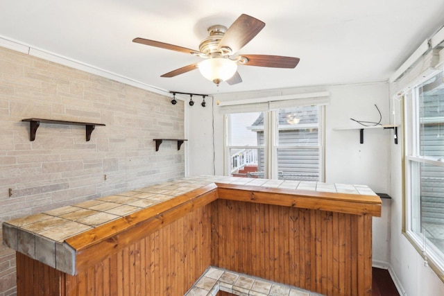 bar with ceiling fan and tile counters