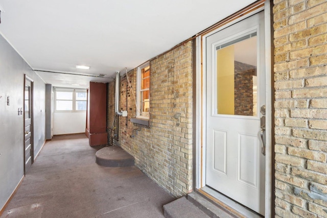 hallway featuring brick wall and carpet