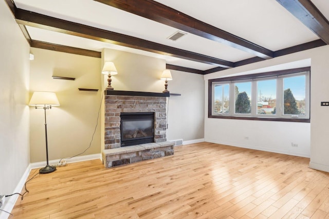 unfurnished living room featuring a brick fireplace, beam ceiling, and light hardwood / wood-style flooring