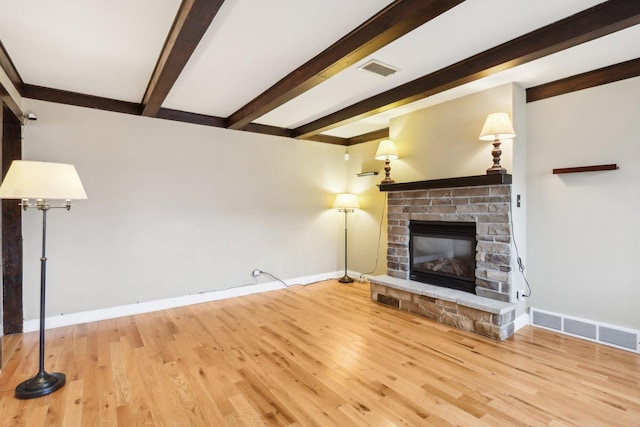 unfurnished living room featuring beamed ceiling, a fireplace, and light wood-type flooring