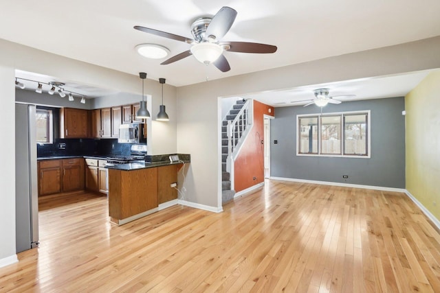 kitchen featuring stainless steel appliances, pendant lighting, light wood-type flooring, and kitchen peninsula