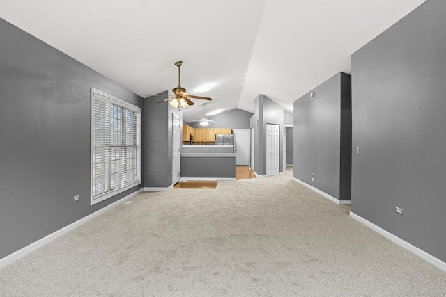 unfurnished living room featuring ceiling fan, vaulted ceiling, and light carpet