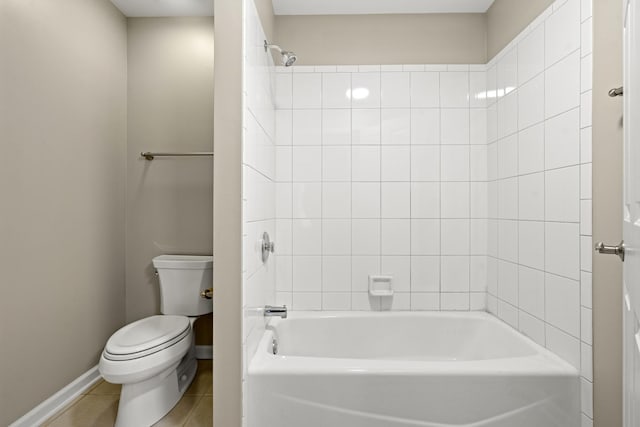 bathroom with tile patterned flooring, tiled shower / bath, and toilet