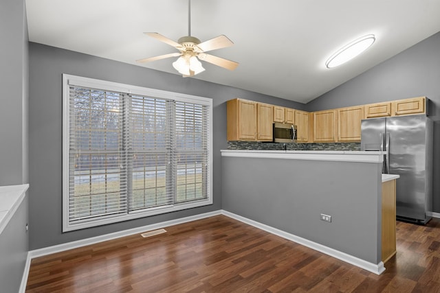 kitchen featuring stainless steel appliances, dark hardwood / wood-style floors, vaulted ceiling, kitchen peninsula, and light brown cabinets