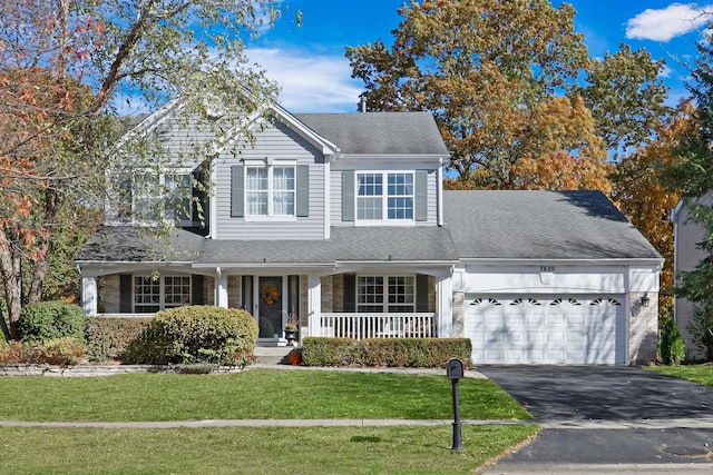 view of front property with a porch, a garage, and a front yard