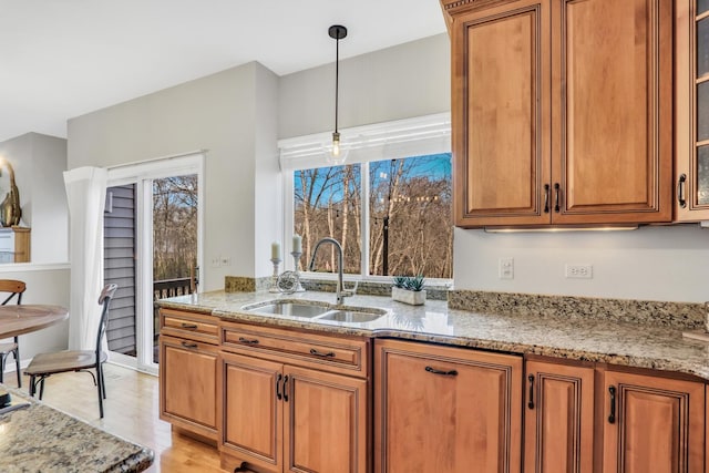 kitchen with pendant lighting, sink, and light stone counters