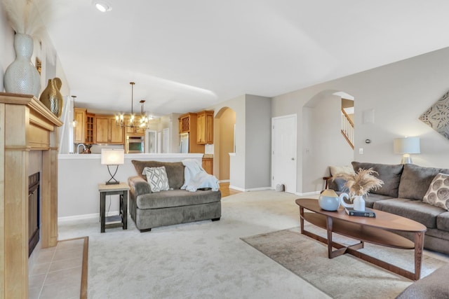 living room with an inviting chandelier, a fireplace, and light carpet