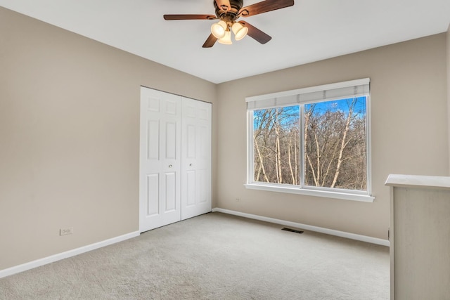 unfurnished bedroom featuring light colored carpet, ceiling fan, and a closet