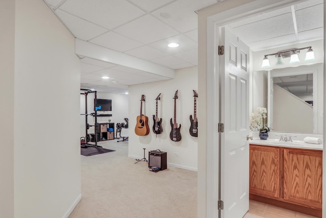 corridor with sink, light colored carpet, and a drop ceiling