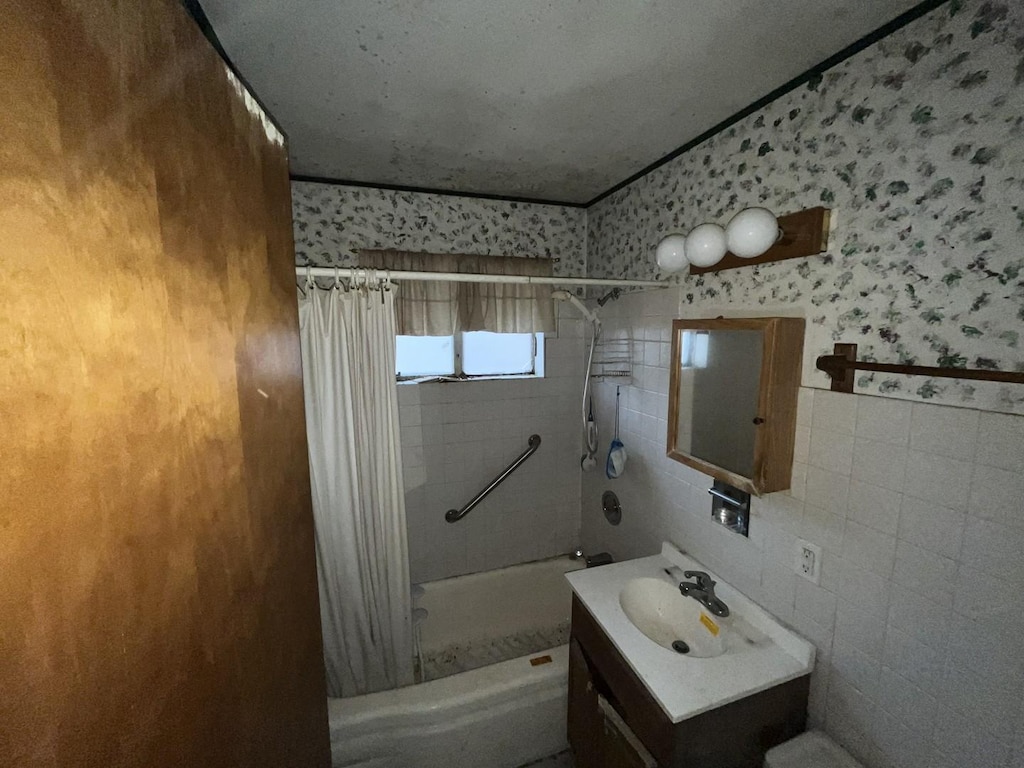 bathroom with shower / bath combination with curtain, vanity, and tile walls