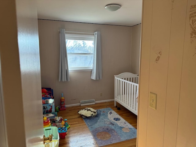 bedroom featuring a crib and wood-type flooring