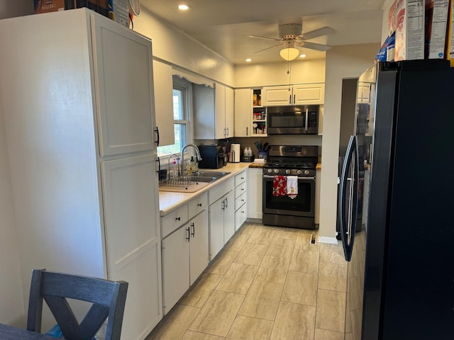 kitchen with stainless steel appliances, white cabinetry, sink, and ceiling fan