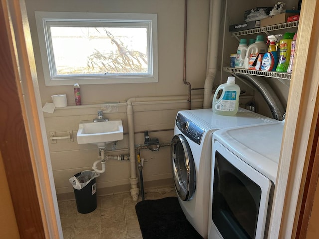 laundry room featuring tile patterned flooring, sink, and washing machine and clothes dryer