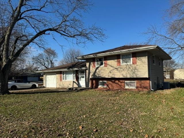 split level home with a garage, central AC unit, and a front lawn