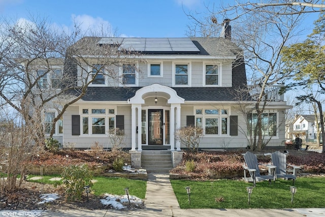 view of front of house with a front yard and solar panels