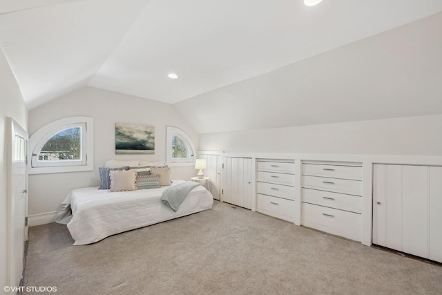 bedroom with multiple windows, lofted ceiling, and light colored carpet