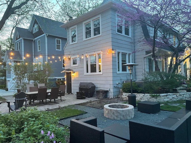 rear view of property featuring a patio and a fire pit