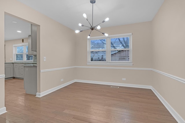 unfurnished dining area with light hardwood / wood-style flooring and a chandelier