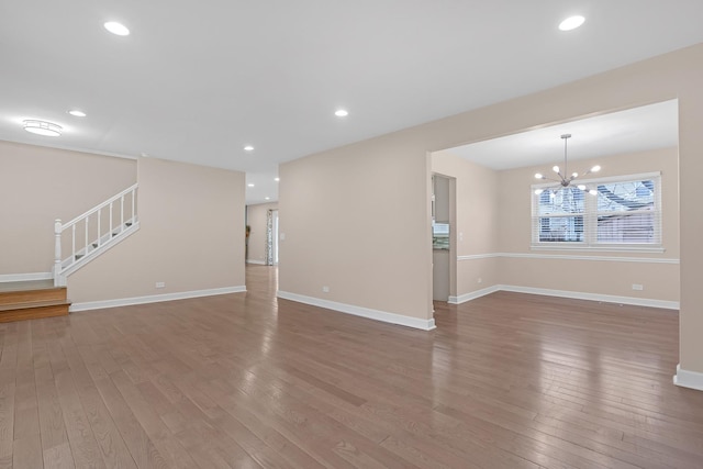 unfurnished living room featuring an inviting chandelier and hardwood / wood-style floors