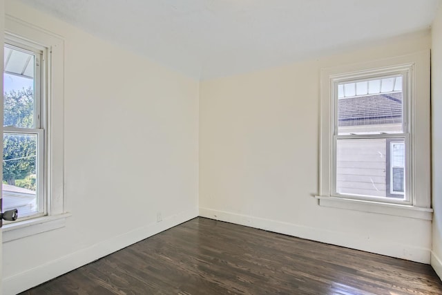 empty room featuring a healthy amount of sunlight and dark hardwood / wood-style floors