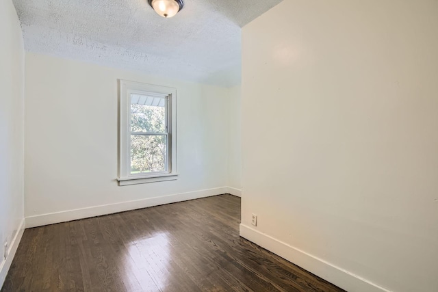 empty room featuring dark wood-type flooring and a textured ceiling