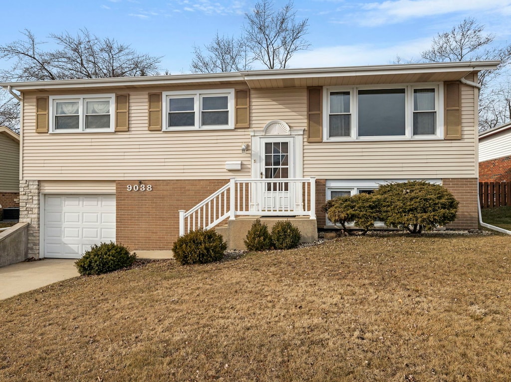 bi-level home featuring a garage and a front lawn