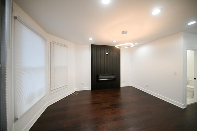 unfurnished room with a large fireplace and dark hardwood / wood-style floors