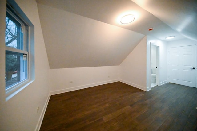 bonus room with dark hardwood / wood-style flooring and vaulted ceiling