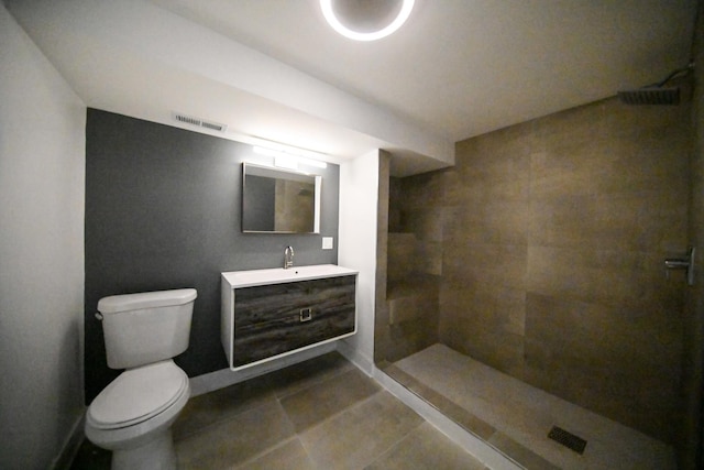 bathroom featuring vanity, toilet, tile patterned flooring, and a tile shower