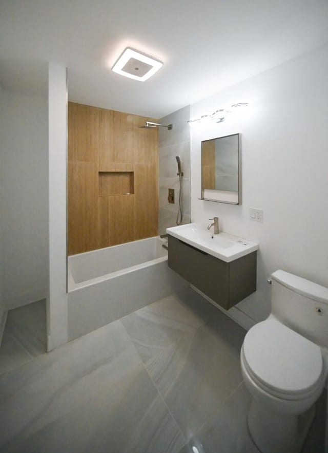 full bathroom featuring vanity, tiled shower / bath, and toilet