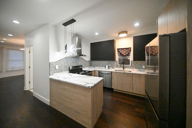 kitchen with appliances with stainless steel finishes, decorative light fixtures, tasteful backsplash, sink, and wall chimney exhaust hood