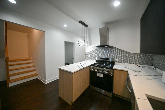 kitchen featuring pendant lighting, backsplash, stainless steel gas range oven, kitchen peninsula, and wall chimney exhaust hood