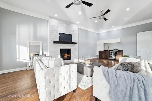 living room featuring bar, ornamental molding, a stone fireplace, and hardwood / wood-style floors